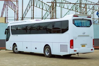 Biały autobus Hyundai zaparkowany przed metalową konstrukcją.