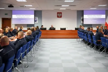 Funkcjonariusze świętokrzyskiej policji w mundurach uczestniczą w odprawie pionu prewencji w sali konferencyjnej z dwoma ekranami projekcyjnymi.