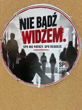 Plakat profilaktyczny szkoły SP9 w Kielcach przyczepiony do tablicy korkowej, zachęcający do reagowania na przemoc.