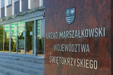 Wejście do siedziby Urzędu Marszałkowskiego Województwa Świętokrzyskiego z herbem regionu na ścianie z czerwonego granitu.