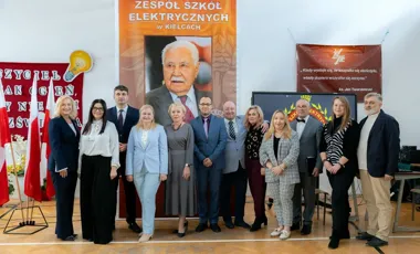 Grupa osób pozuje do pamiątkowego zdjęcia w auli Zespołu Szkół Elektrycznych w Kielcach, podczas uroczystości szkolnej.