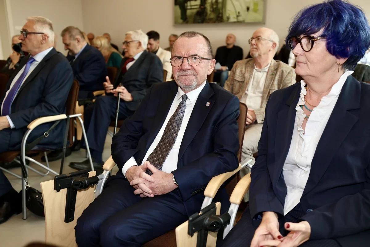 Uczestnicy oficjalnego spotkania siedzą w krzesłach w sali konferencyjnej.